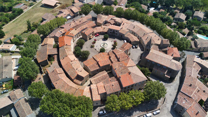 Wall Mural - Aerial shot of a medieval round village with red tile roofs surrounded by green fields and trees