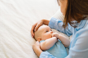 Wall Mural - A young mother is play with little baby boy. Mother of a nursing baby. Happy motherhood. The family is at home. Portrait of a happy mother and child.