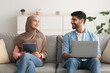© Prostock-studio - Middle Eastern Couple Using Laptop And Tablet Computers At Home