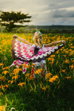 Blond Girl Child Pretend Play With Butterfly Wings In Flower Field