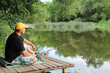 Man fishing on river wooden pier in summer wood