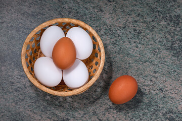 Poster - several fresh chicken eggs in a straw basket on a wooden background. Healthy eating concept.