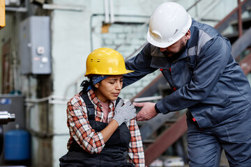 foreman in hardhat and workwear standing by female engineer with contusion touching her shoulder aga