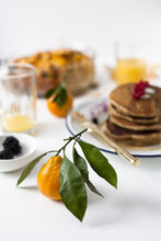 Closeup Of Satsuma Orange With Leaves Brunch And Pancake With Berries On White Table