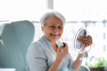 Wall Mural - Senior Woman Doing Makeup In Front Of Mirror
