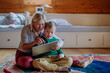 © Halfpoint - Child with Down syndrome sitting on floor and using tablet with grandmother at home.