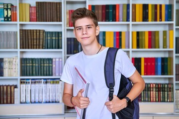 Wall Mural - Portrait of male teenage student looking into the camera in library