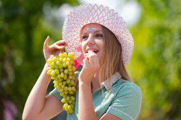 Young woman eating fresh grapes. Portrait of attractive caucasian smiling woman eating grapes. Woman is harvest grapes at farm.