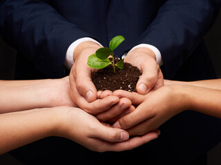 Poster - Care and conserve. Shot of a group of hands holding a pile of soil with a plant in.