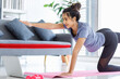 © Bangkok Click Studio - Asian young happy peaceful calm healthy female model in casual sporty outfit smiling doing yoga stretching exercise on mat learning studying online pilates class via laptop computer in living room