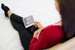 © Supagrit Ninkaesorn - Pregnant woman sitting on bed and looking at her ultrasound image of her child in her belly.