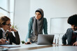 © Drazen - Young Muslim businesswoman uses laptop while discussing with colleagues on meeting in the office.