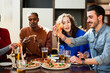 © Pintau Studio - Multiethnic group of friends sitting at table eating . The pieces of pizzas have stringy cheese.