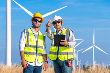 Wall Mural - Engineer wearing uniform ,helmet hold document inspection work in wind turbine farms rotation to generate electricity energy. Green ecological power energy generation wind sustainable energy concept.