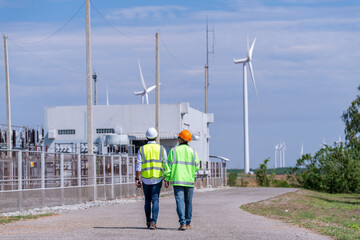 Wall Mural - Engineer wearing uniform ,helmet hold document inspection work in wind turbine farms rotation to generate electricity energy. Green ecological power energy generation wind sustainable energy concept.