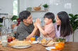 © Shisu_ka - Asian family breakfast at happy home. Parents and children enjoy eating together, talking with laughter and good atmosphere. Father plays with son playfully at kitchen table