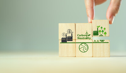 Canvas Print - Carbon neutral balancing CO2  emission offset concept. Green indrustry, trees, renewable energy to absorb CO2 in compensation of same amount produced. Hand holds wooden cube with carbon offset icon.