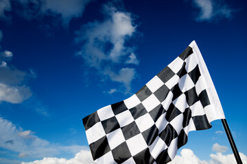 Checkered race flag waving on sky