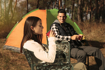 Canvas Print - Couple resting in camping chairs and enjoying hot drink outdoors