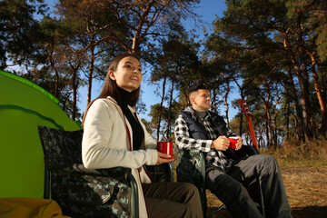 Canvas Print - Couple resting in camping chairs and enjoying hot drink outdoors