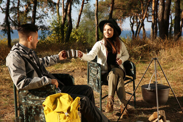 Sticker - Couple resting in camping chairs and enjoying hot drink near bonfire outdoors