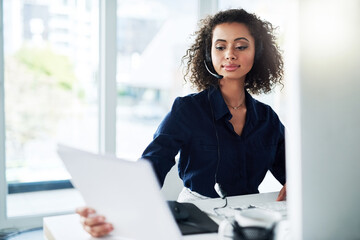 Reading over her reports. Cropped shot of an attractive young female call center agent reading some paperwork while working in her office.