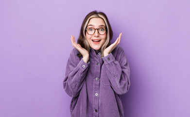 Wall Mural - pretty caucasian woman feeling shocked and excited, laughing, amazed and happy because of an unexpected surprise