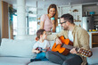 © Dragana Gordic - Father At Home With Son Teaching Him To Play Acoustic Guitar In Livingroom. First guitar class. Shot of a boy learning to play guitar from his father