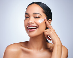 Frantically rebooting my life. Portrait of an attractive young woman applying moisturiser against a grey background.