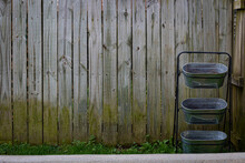Stacked Garden And Flower Pots In Front Of A Moldy Wooden Fence At The Start Of The Gardening Season