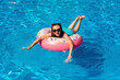 © Yevhenii Rukavitsyn - young woman in bikini swims on the inflatable water donut in the swimming pool.
