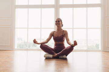 Wall Mural - Young woman sitting in lotus position on floor