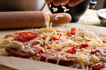 Wall Mural - Raw pizza, preparation in traditional style. Adding cheese on a pizza dough.