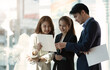 © wichayada - Group of businesspeople using a report together in front of office building windows overlooking the city