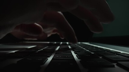 Macro dolly shot sliding footage of male hands typing on laptop keyboard in dark office. Male fingers touch keyboard notebook. Freelance working, online education. Close up. Slow motion.