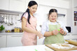 mother support down syndrome teenage girl or her daughter using a mold made of rolled dough on kitchen table