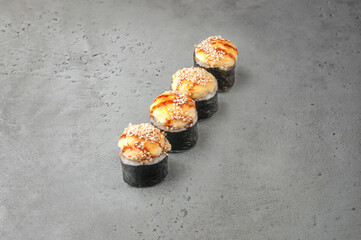 baked maki sushi with salmon and teriyaki sauce on gray background