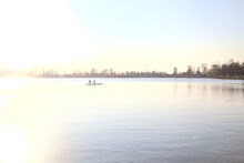 Rowers On A Kayak On A Lake Counterlit By The Sun