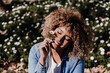 © Eva - smiling hispanic woman with eyes closed in park enjoying sunny day. Spring flowers background