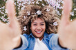 © Eva - top view of happy hispanic woman with afro hair lying on grass among pink blossom flowers.Springtime