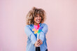 © Eva - beautiful happy hispanic woman with afro hair holding colorful pinwheel. pink background,wind energy