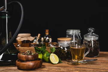 Canvas Print - Dry tea, limes near hookah on wooden surface isolated on black.