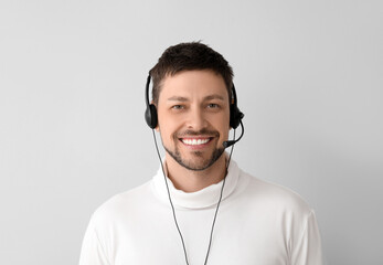 Wall Mural - Smiling consultant of call center in headset on light background