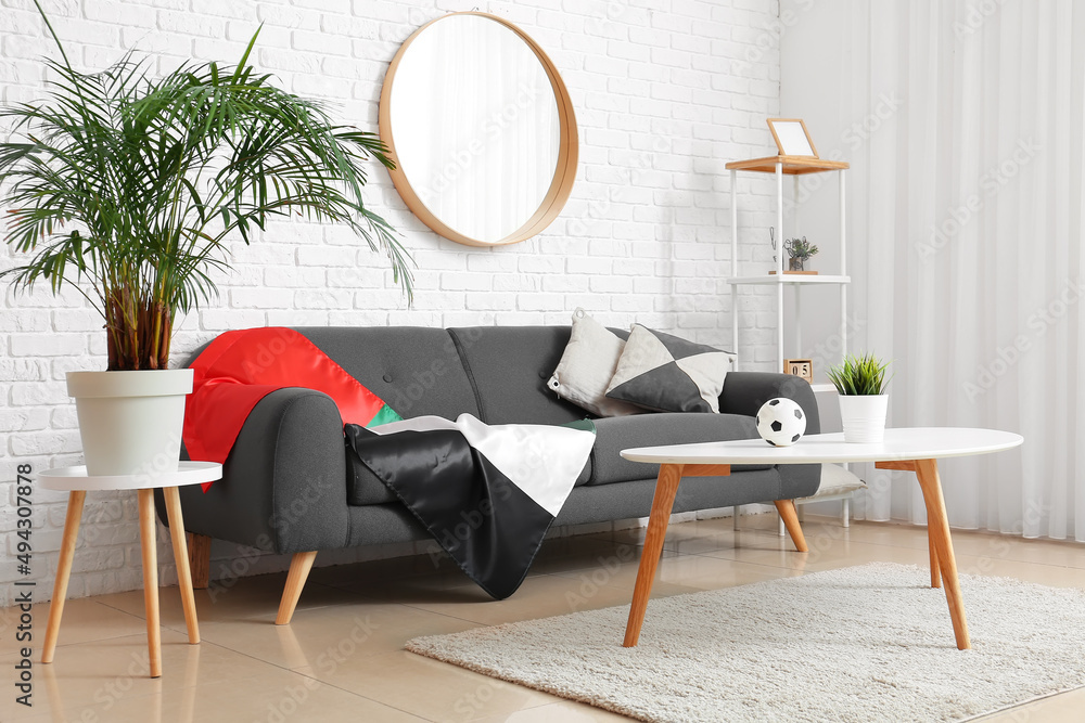 Interior of light living room with black sofa and UAE flag
