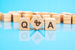 q and a word is made of wooden building blocks lying on the bright blue table, concept