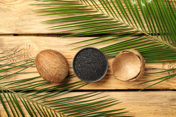 Wall Mural - Composition with coconut activated carbon and palm leaves on wooden background