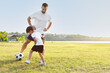 © Pixel-Shot - Little boy playing soccer with his father on field