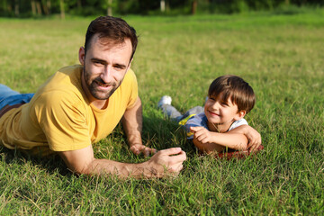 Sticker - Little boy with rugby ball and his father lying on green grass in park