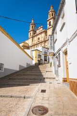 Wall Mural - Narrow street with stairs in the old town of Olvera with the beautiful hurch of Our Lady of the Incarnation, 18th century, in neoclassical style in the background, Cadiz province, Andalusia, Spain