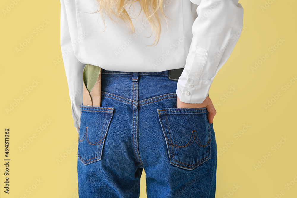 Reusable menstrual pad in female jeans pocket on yellow background